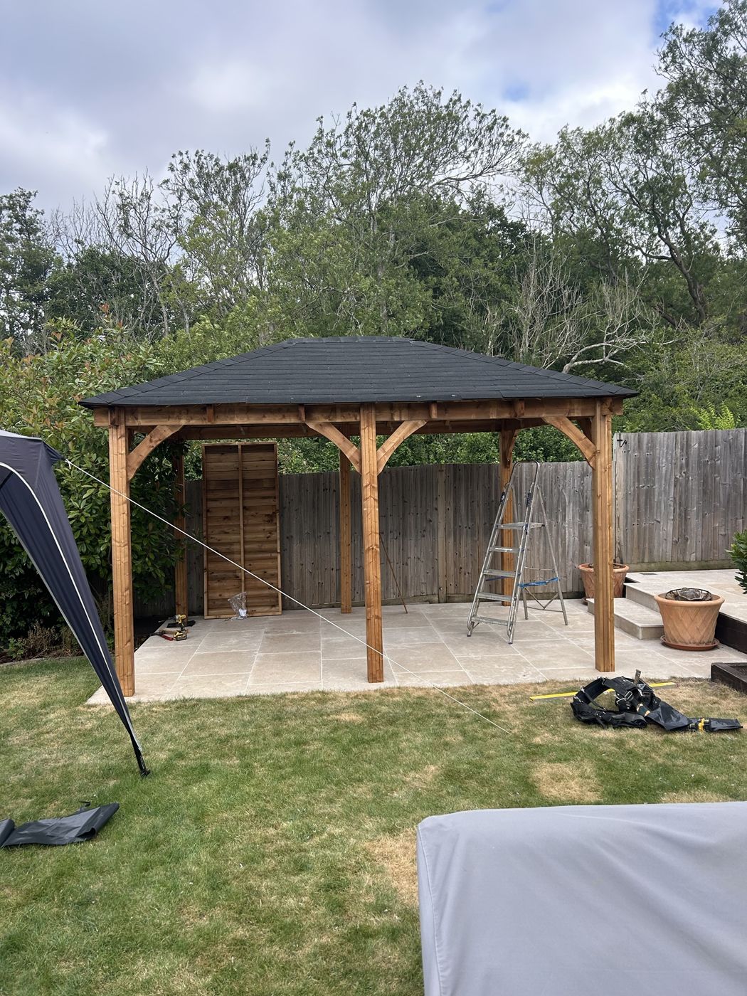 Timber gazebo with curved braces and a hipped roof, built on a stone patio