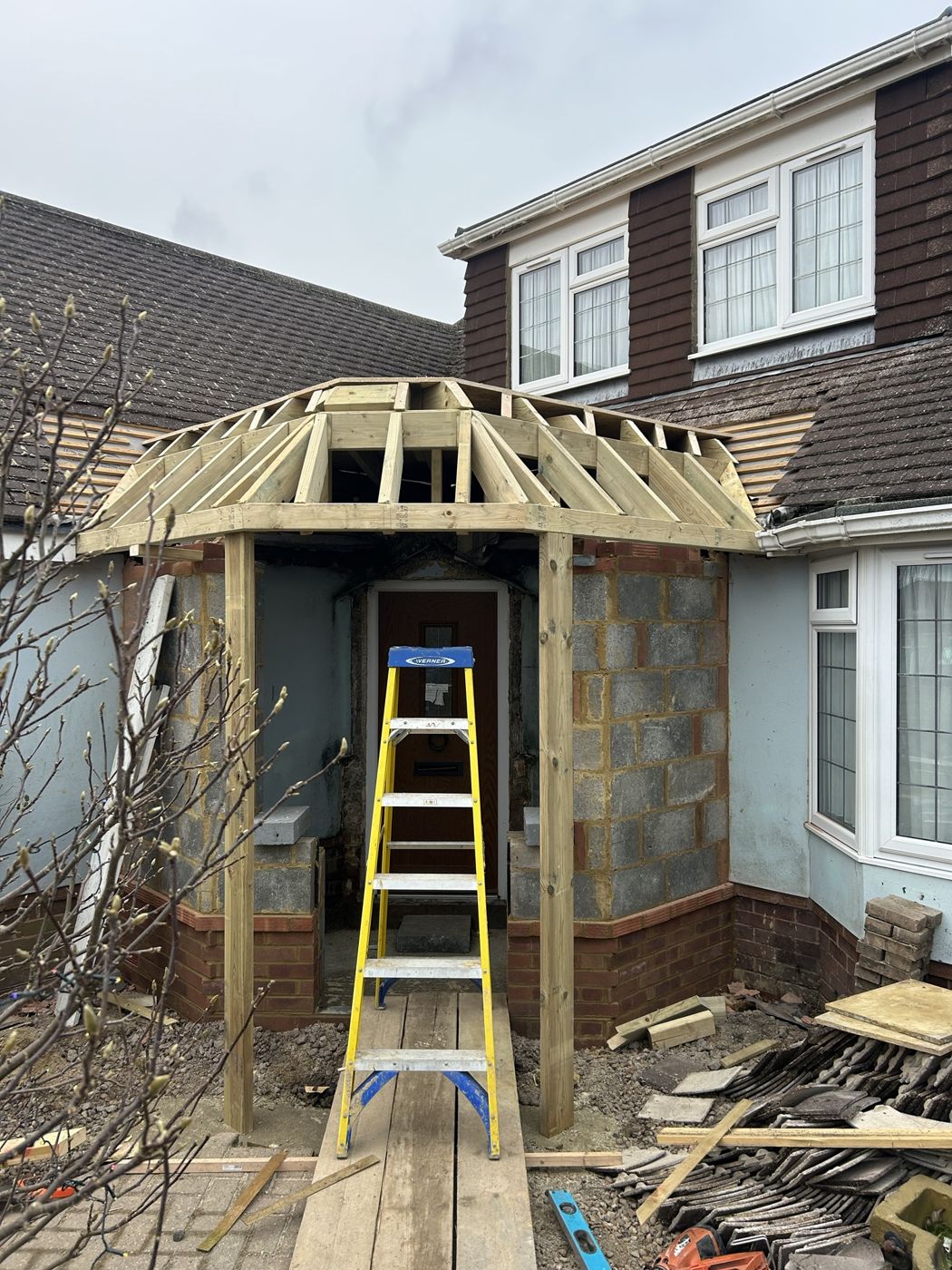 Hand-cut timber roof frame going up over a new front porch